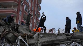 People and emergency teams search for people in a destroyed building in Adana, Turkey.