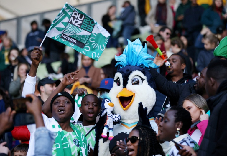 Soccer Football - FIFA Women’s World Cup Australia and New Zealand 2023 - Group B - Nigeria v Canada - Melbourne Rectangular Stadium, Melbourne, Australia - July 21, 2023 Nigeria fans in the stands with Tazuni the penguin, the official mascot of the FIFA women’s world cup REUTERS/Asanka Brendon Ratnayake