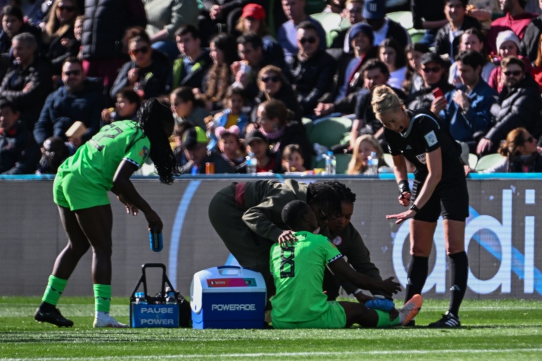 Referee Lina Lehtovaara of Finland (R) speaks with Nigeria's forward #08 Asisat Oshoala (C) while receiving medical attention on the pitch during the Australia and New Zealand 2023 Women's World Cup Group B football match between Nigeria and Canada at Melbourne Rectangular Stadium, also known as AAMI Park, in Melbourne on July 21, 2023. (Photo by WILLIAM WEST / AFP)