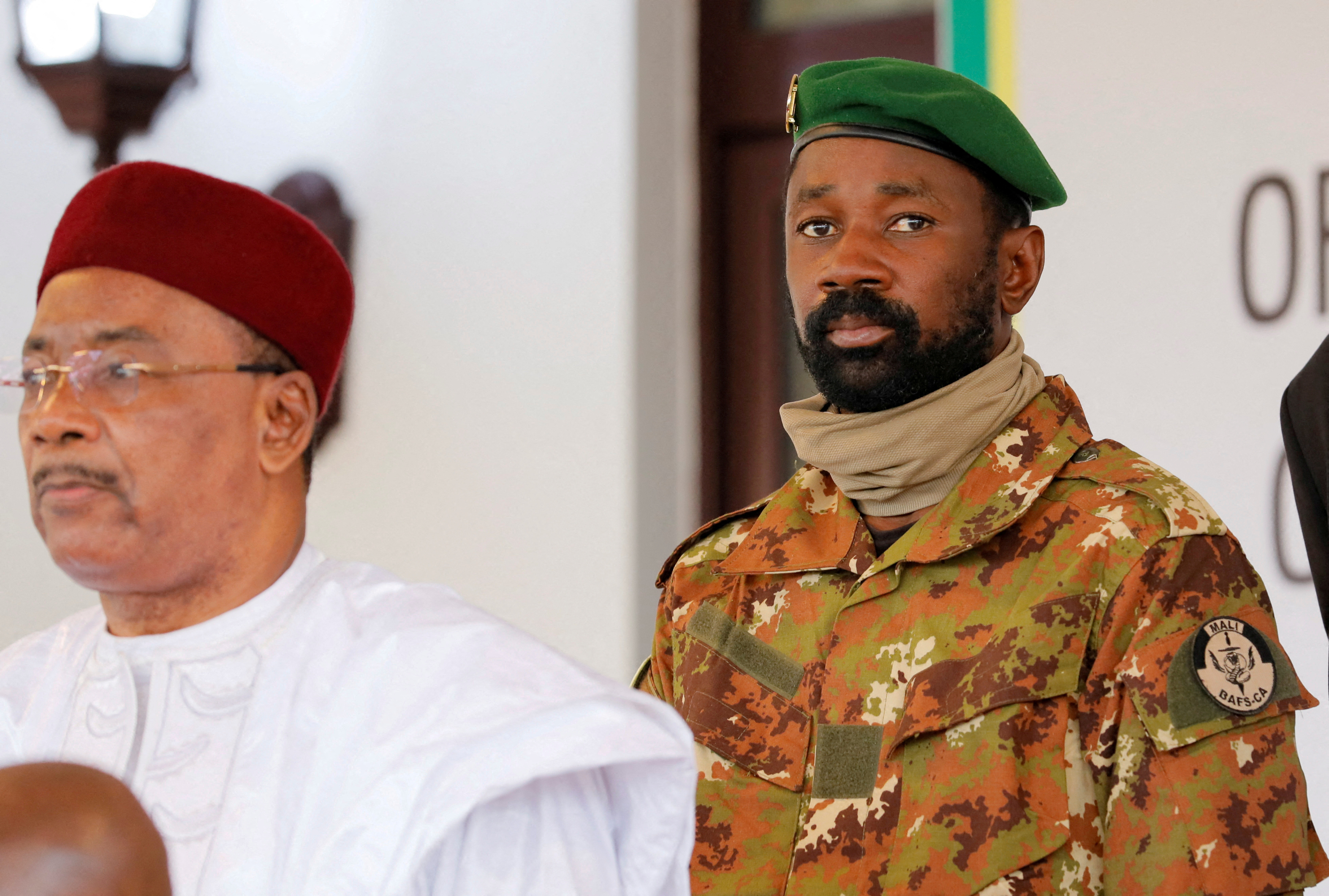 Colonel Assimi Goita, leader of Malian military junta, looks on while he stands behind Niger's President Mahamadou Issoufou during a photo opportunity after the Economic Community of West African States (ECOWAS) consultative meeting in Accra