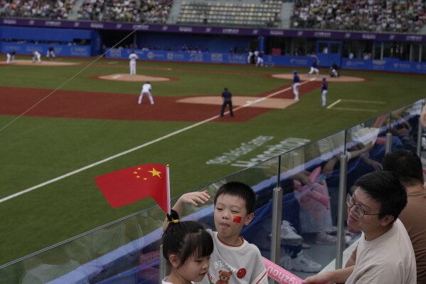 Chinese children with Chinese national flag and decals attend a stage group round B Baseball Men game between Taiwan and Hong Kong for the 19th Asian Games in Hangzhou, China on Tuesday, Oct. 3, 2023. At the Asian Games China has been going out of its way to be welcoming to the Taiwanese athletes, as it pursues a two-pronged strategy with the goal of taking over the island, which involves both wooing its people while threatening it militarily. (AP Photo/Ng Han Guan)