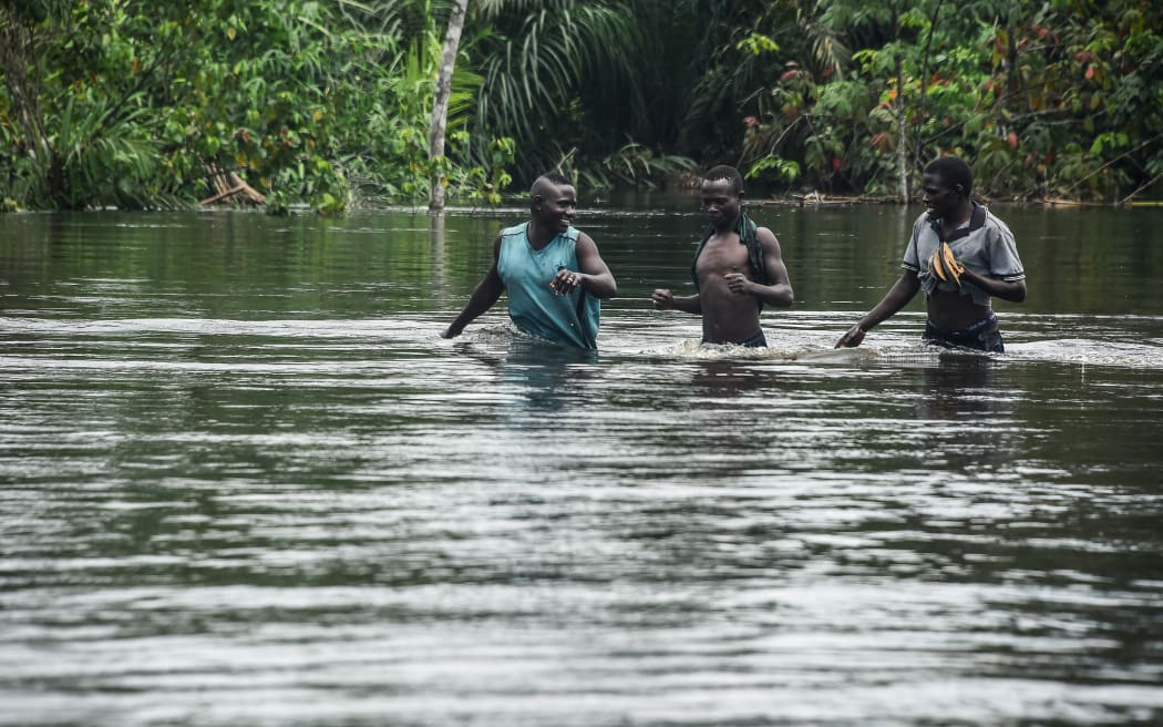 People walk along the East-West highway severed by flooding in Niger, Nigeria, in 2022.