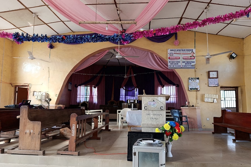 An open room with church pews and pink decorations on the ceiling.