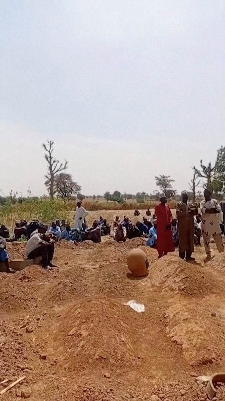 People standing around graves in Nigeria following this week's attacks